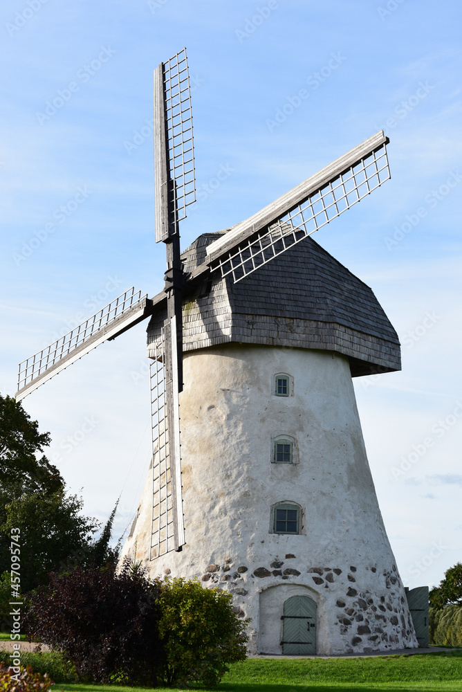 a beautiful windmill at the top of a hill with big wings and a blue sky