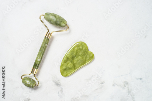 Fototapeta Naklejka Na Ścianę i Meble -  Jade roller and gua sha stone massager at white bath towel. Anti aging therapy. Top view with copy space..