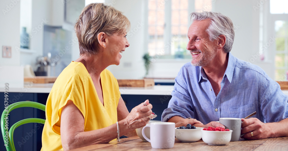 Retired Couple Sitting Around Table At Home Having Healthy Breakfast Together