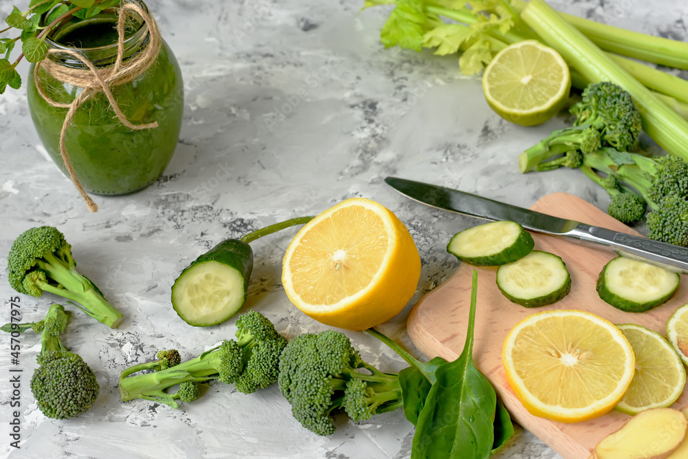 Brocoli, cucumber lemon ginger - green vegetable ingredients for a healthy smoothie. different vegetables on a gray concrete background and a green smoothie. Brocoli, cucumber lemon ginger - green vegetable ingredients for a healthy smoothie. different vegetables on a gray concrete background and a green smoothie.