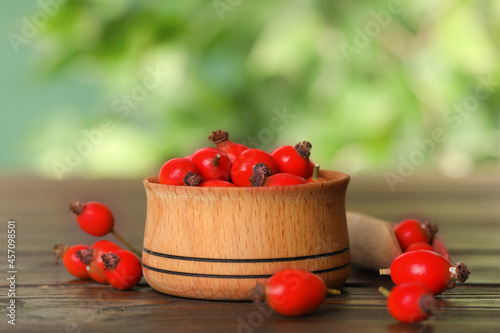 Ripe rose hip berries with bowl on wooden table