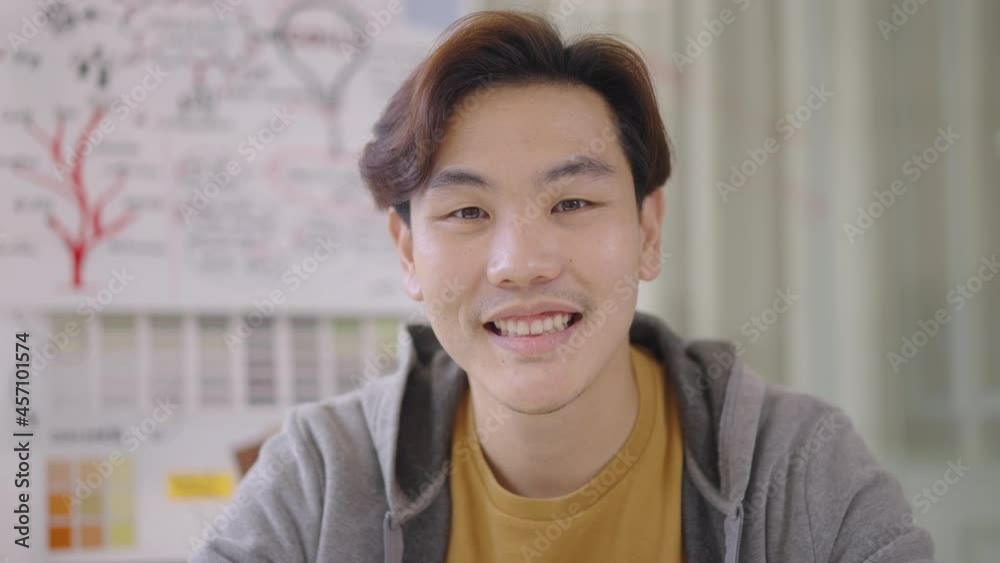 Close up portrait young Asian man smiling to camera in office Close up portrait young Asian man smiling to camera in office