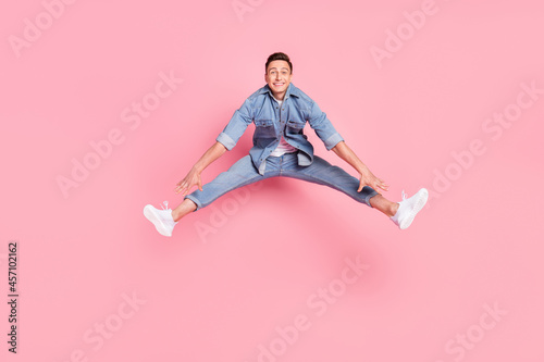 Full size photo of young funky funny careless smiling guy jumping rejoice energetic isolated on pink color background