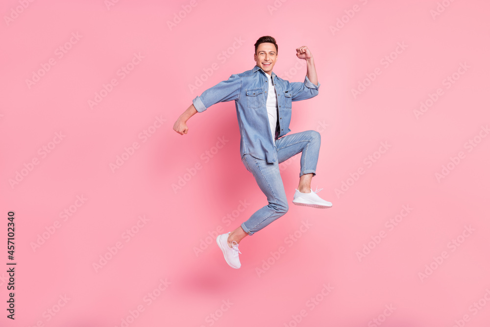 Full size photo of smiling positive handsome guy jumping raise fist in victory triumph isolated on pink color background