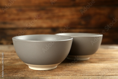 Stylish empty ceramic bowls on wooden table. Cooking utensils
