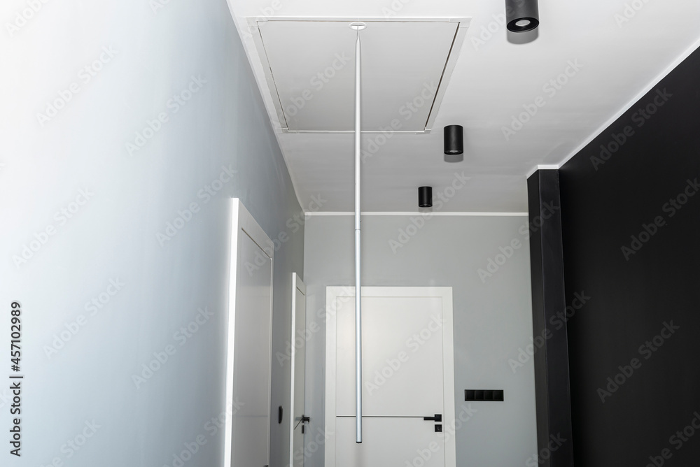 Folding metal stairs to the attic in the ceiling, closed hatch with a tube for opening, modern look. Folding metal stairs to the attic in the ceiling, closed hatch with a tube for opening, modern look.