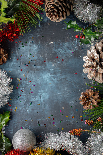 marco navideño con piñas de pino, acebo, espumillón, ramas de pino y bola decorativa, con espacio en blanco en el centro photo
