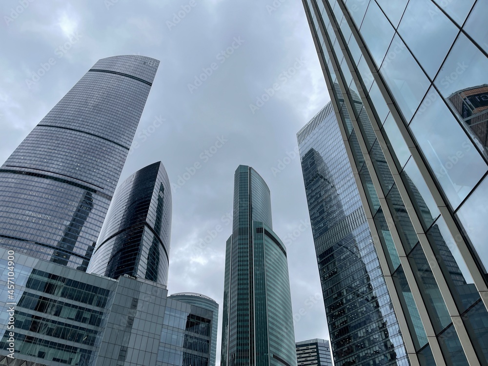 Facade of modern skyscraper with glass walls. From below of contemporary tall skyscraper with glass walls against cloudy sky in downtown Facade of modern skyscraper with glass walls. From below of contemporary tall skyscraper with glass walls against cloudy sky in downtown