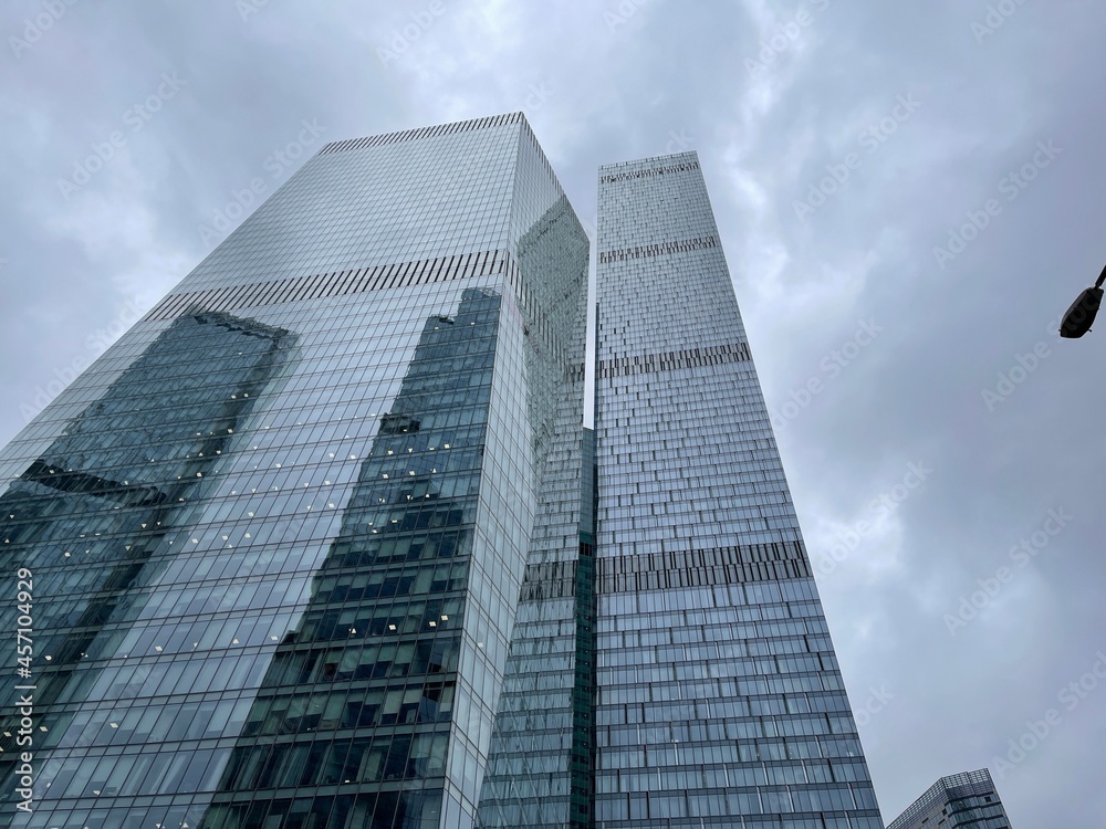 Facade of modern skyscraper with glass walls. From below of contemporary tall skyscraper with glass walls against cloudy sky in downtown