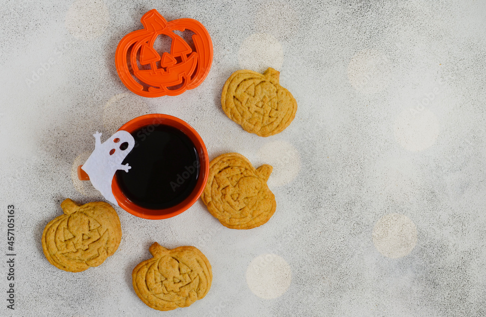 Breakfast or morning for halloween holiday, homemade pumpkin shaped cookies and bakeware cutting dish with a cup of coffee on concrete background Breakfast or morning for halloween holiday, homemade pumpkin shaped cookies and bakeware cutting dish with a cup of coffee on concrete background