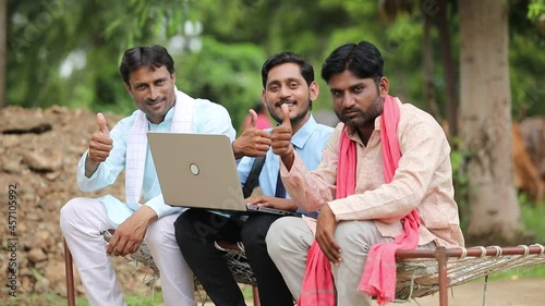 Young indian banker or agronomist showing some detail to farmers in laptop at home
