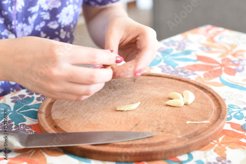 a woman chopping pieces of garlic on a wooden board