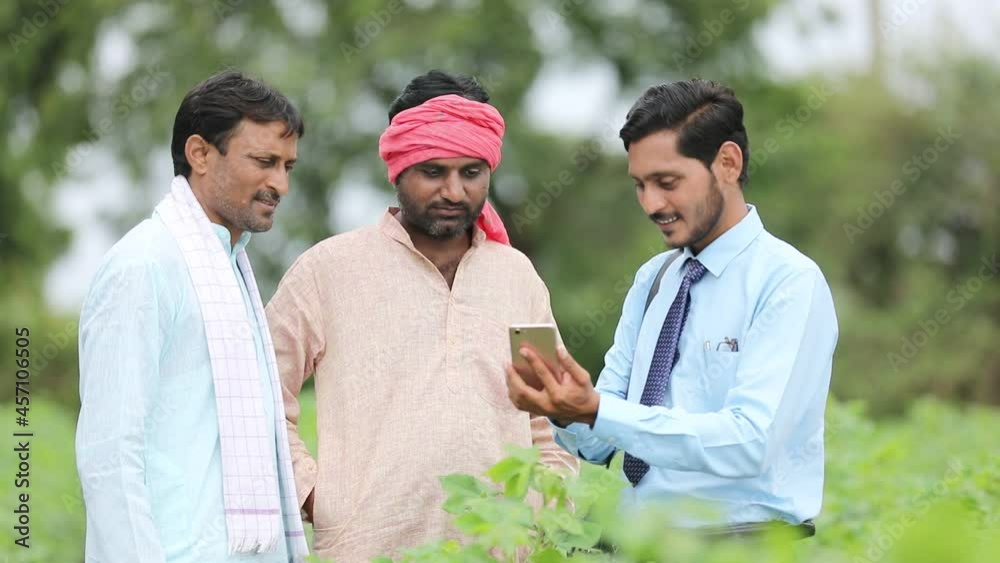 Young indian agronomist or banker showing some information to farmer in smartphone at agriculture field. Young indian agronomist or banker showing some information to farmer in smartphone at agriculture field.