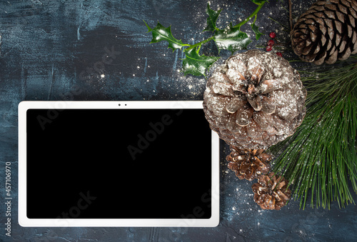 tablet blanca con pantalla vacía y adornos de Navidad sobre fondo oscuro con textura photo