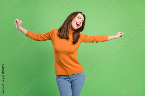 Portrait of attractive cheerful carefree dreamy girl dancing having fun resting isolated over green color background