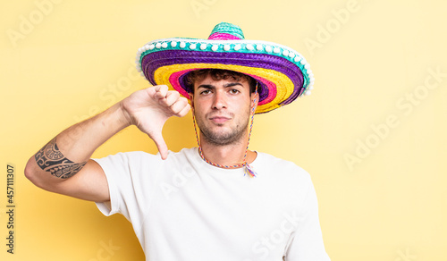 young handsome man feeling cross,showing thumbs down. mexican hat concept photo