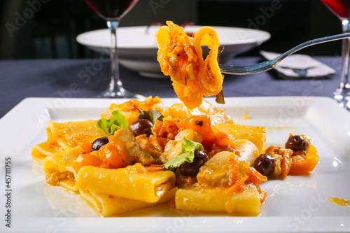 Piatto da ristorante con pasta di Gragnano con pomodoro giallo, olive nere e zucca photo