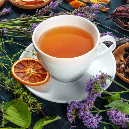 Tea with herbs, flowers and fruit, on a dark rustic wooden background, hot autumn beverage, square shot