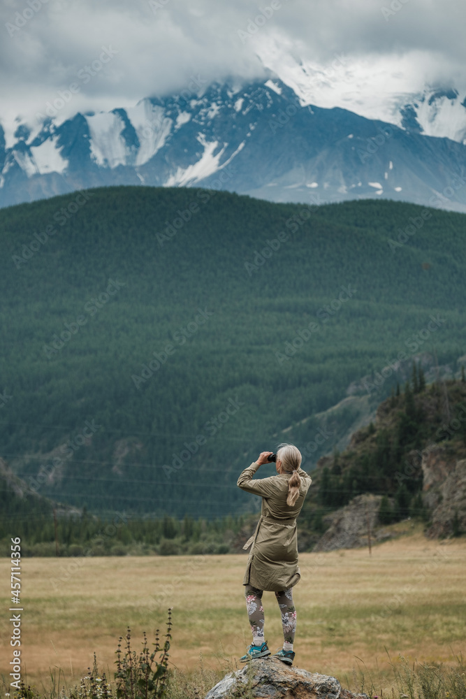 Girl with binoculars standing in the mountains of the Altai Republic Girl with binoculars standing in the mountains of the Altai Republic