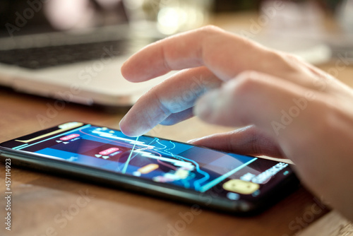 A man at home using a smartphone to check his stocks and investments. Trading and investing on the go using current technology. Generic trading chart on the phone created specifically for the photo.