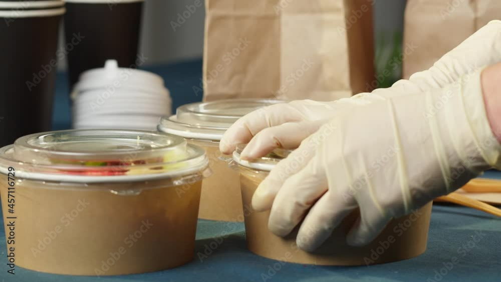 Food delivery of traditional Hawaiian cuisine. Packaging cooked poke bowls into paper bag, wearing protective gloves. Healthy vegetarian eating. Asian vegan raw meal. Delivery services during covid.