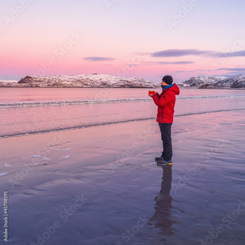 A man warms up with tea. Hot tea on the cold deserted Arctic coast