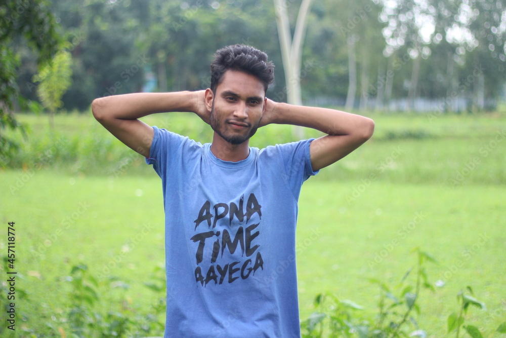 A boy has two hands behind his head and the background behind him blurred A boy has two hands behind his head and the background behind him blurred