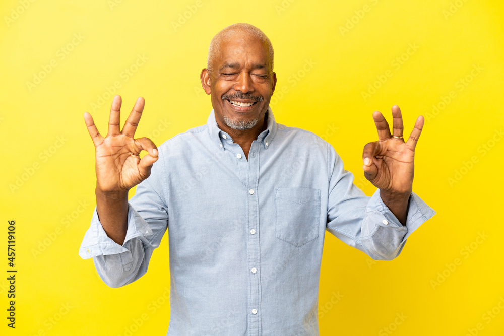 Cuban Senior isolated on yellow background in zen pose
