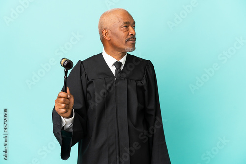 Judge senior man isolated on blue background looking to the side photo