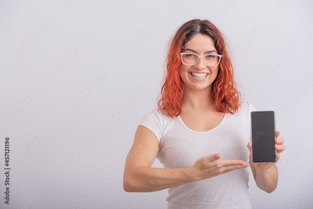 A Caucasian woman points to a smartphone with a blank screen on a white background A Caucasian woman points to a smartphone with a blank screen on a white background