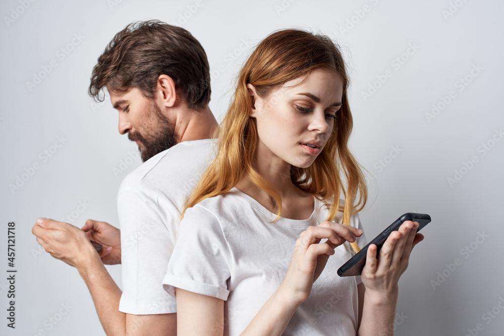 man and woman in white T-shirts with phones in their hands studio lifestyle man and woman in white T-shirts with phones in their hands studio lifestyle