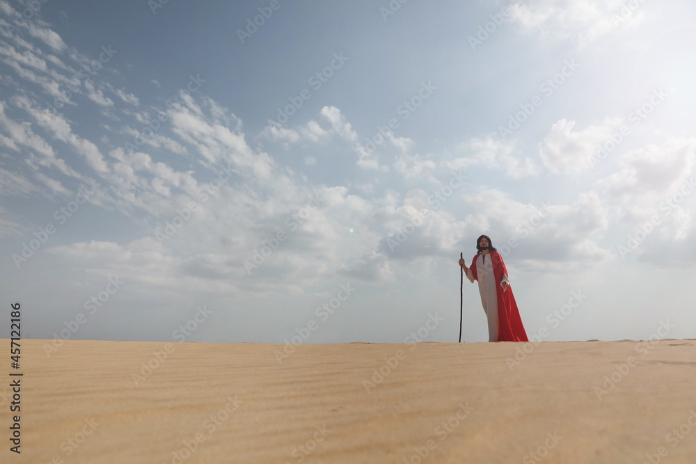 Fototapeta premium Jesus Christ walking with stick in desert. Space for text