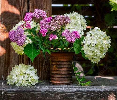 Still life with a bouquet of white and lilac flowers in a ceramic vase. Blooming hydrangea. Vintage.