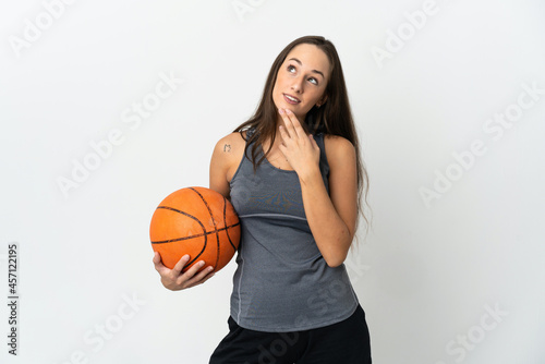 Young woman playing basketball over isolated white background looking up while smiling
