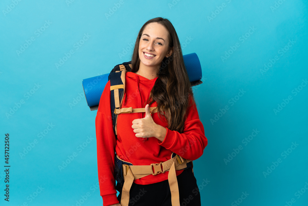 Mountaineer woman with a big backpack over isolated background giving a thumbs up gesture Mountaineer woman with a big backpack over isolated background giving a thumbs up gesture