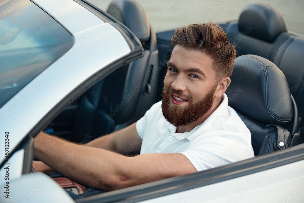 Young european man riding in cabriolet automobile