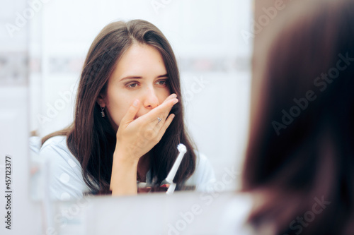 Woman Holding Toothbrush Having a Toothache Looking in the Mirror