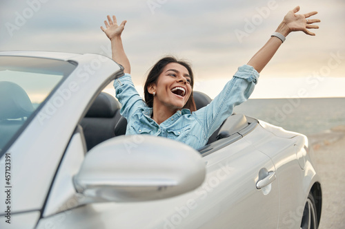 Happy european girl celebrating in cabriolet car