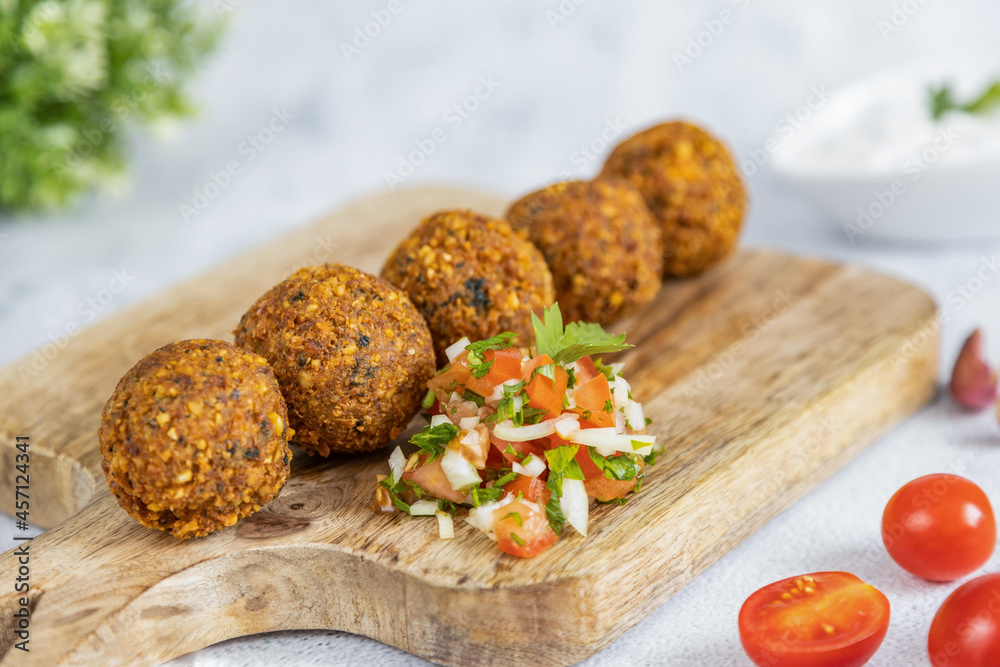 Falafel, a traditional Middle Eastern dish made from chickpeas, served with tomato salad. Vegetarian food. Great healthy snack. Close-up