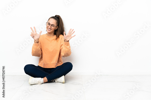 Young woman sitting on the floor counting eight with fingers