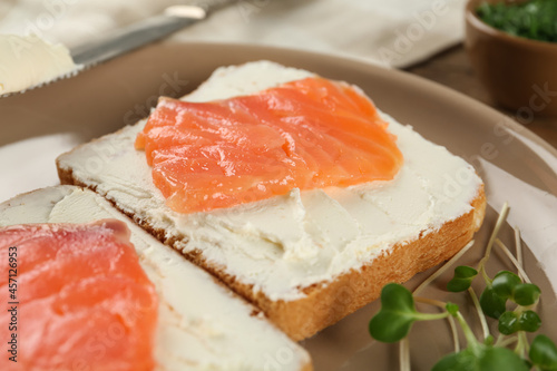 Delicious sandwiches with cream cheese and salmon on plate, closeup