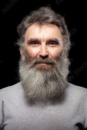 Classic portrait of an elderly man with a gray beard on a black background.