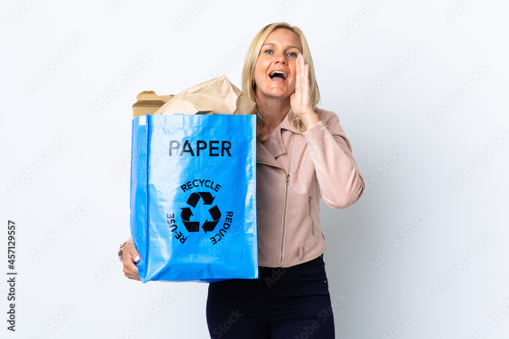 Middle age woman holding a recycling bag full of paper to recycle isolated on white background shouting with mouth wide open Middle age woman holding a recycling bag full of paper to recycle isolated on white background shouting with mouth wide open