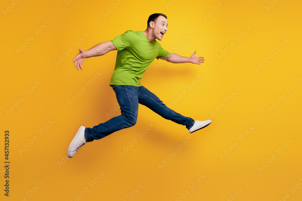 Portrait of sportive energetic guy jump hurry run on yellow wall