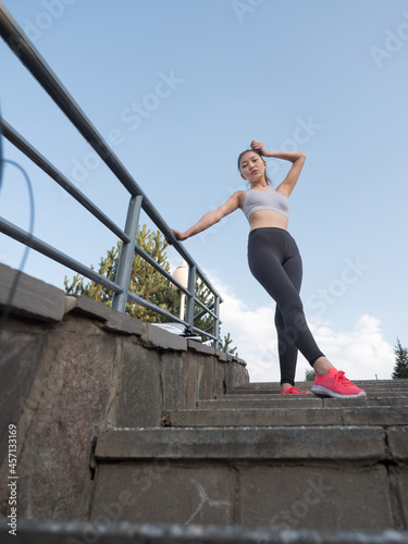 Asian girl in sportswear goes down the stairs in the park, doing sports.