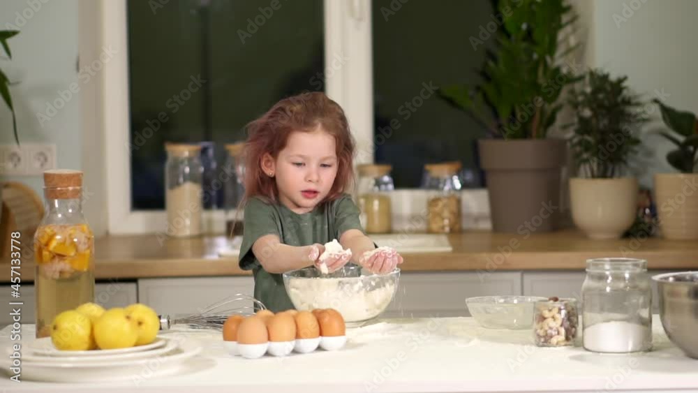 child plays with flour. Little preschool girl learns to prepare dough. Have fun in kitchen with a game. Throw flour splashes in different directions. Clap and laugh. A messy mess. kid stained kitchen. child plays with flour. Little preschool girl learns to prepare dough. Have fun in kitchen with a game. Throw flour splashes in different directions. Clap and laugh. A messy mess. kid stained kitchen.