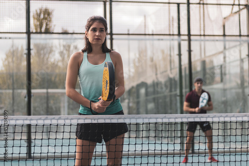 a couple of a boy and a girl playing paddle tennis outdoors. photo