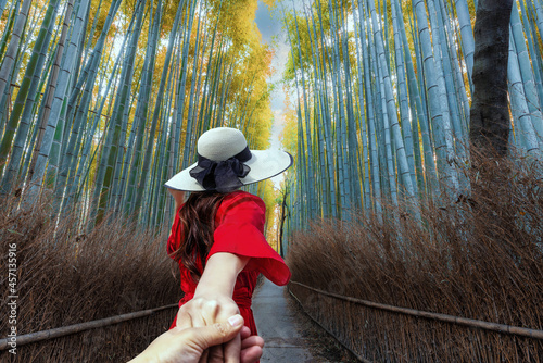 A woman tourist is hand to hand sightseeing and traveling at Arashiyama Bamboo Forest in Kyoto, Japan. photo
