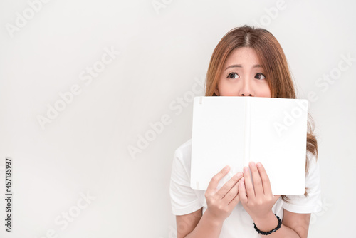 Young attractive asian student holding books in her arm on white background. School girl with a books to read for homework.
