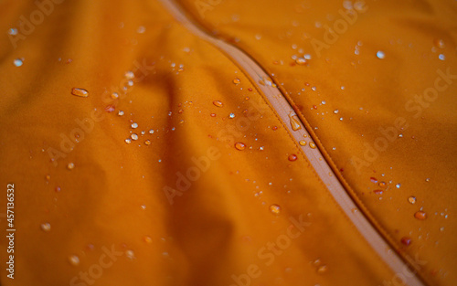 Water drops on a waterproof fabric for mountain clothes. Detail photo of orange wateproof jacket with water droplets on it. Jacket using the gore tex technology. photo